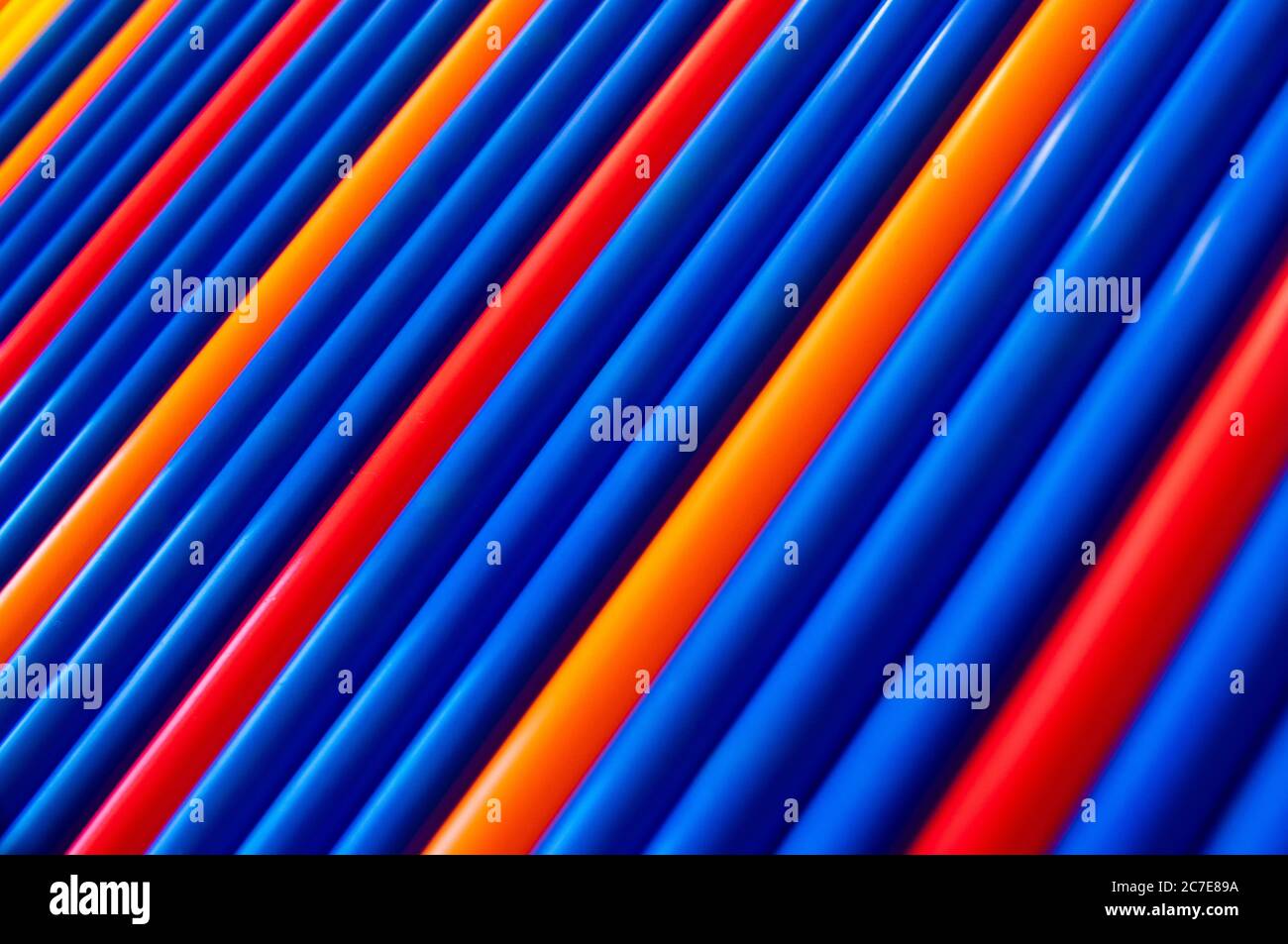 Blue, red, orange pattern plastic tubes straws diagonal background Stock Photo