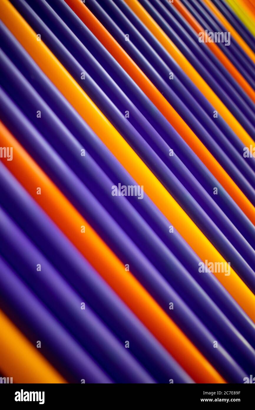 Purple and orange pattern plastic tubes straws diagonal background Stock Photo
