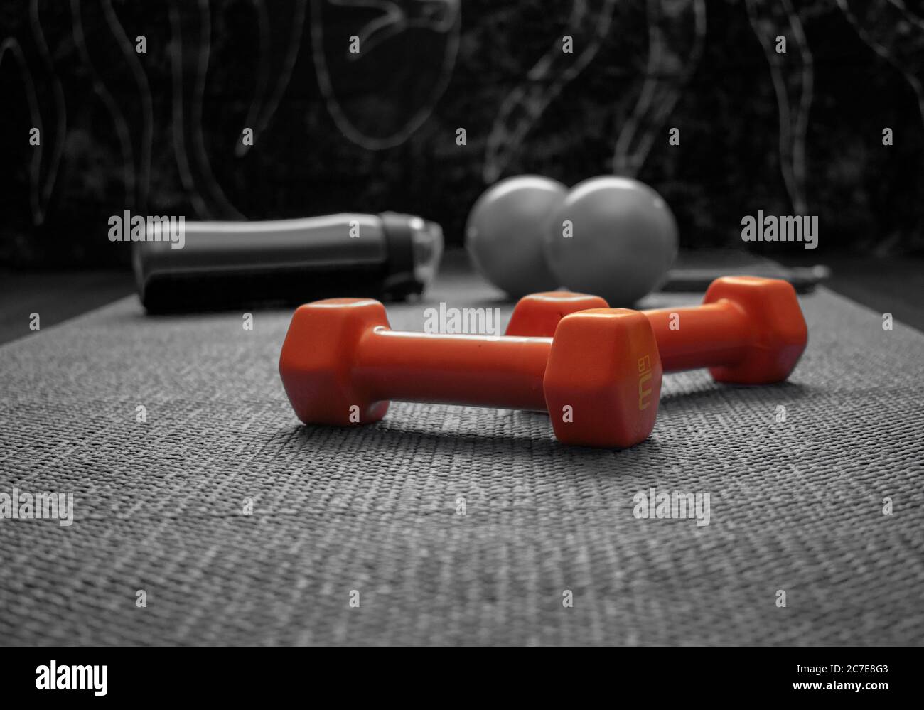 Yoga mat in black and white with isolated orange-colored dumbbells Stock Photo