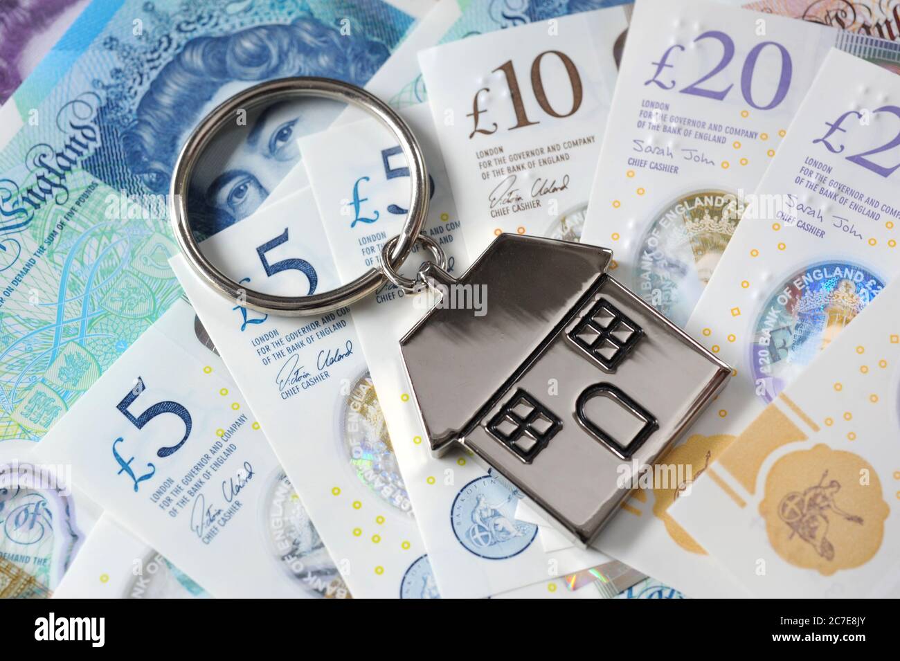 BRITISH MONEY CURRENCY WITH HOUSE KEY RING RE THE ECONOMY COVID 19 CORONAVIRUS CASH JOBS BANKS PENSIONS ETC UK Stock Photo