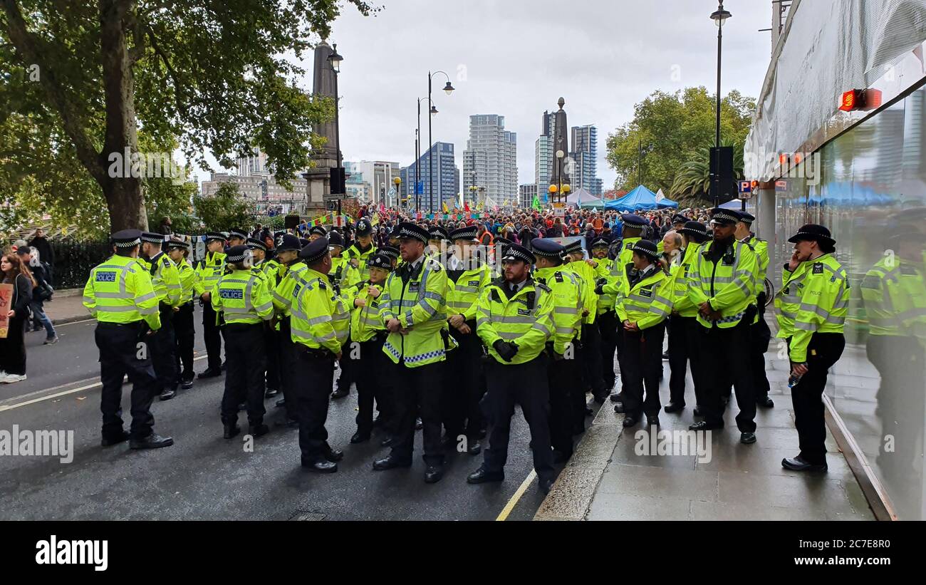 Police officers gathering to prepare to control extinction rebellion protest (visible in background) in central London Stock Photo