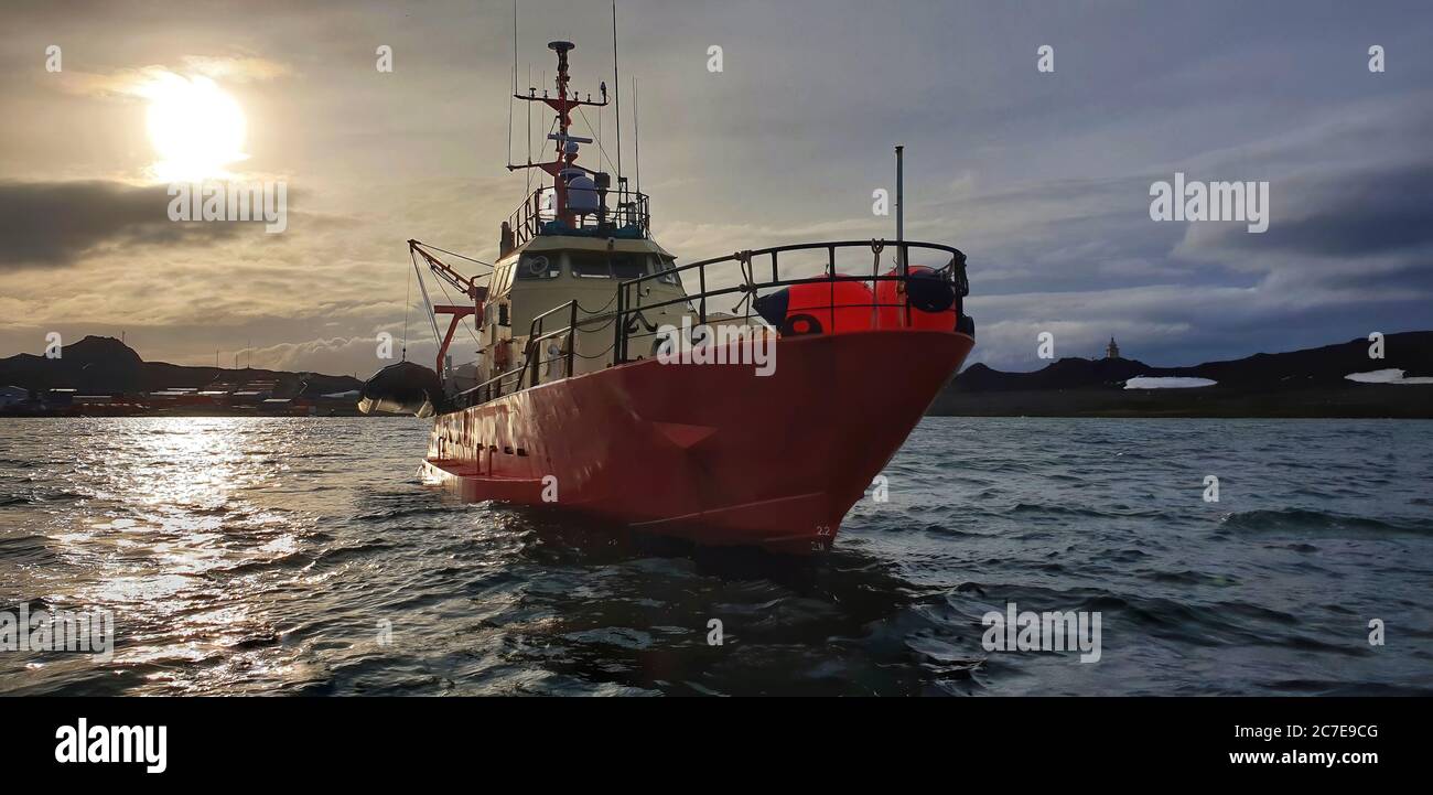 Scientific research vessel in Antarctica with Chilean research base in the background Stock Photo