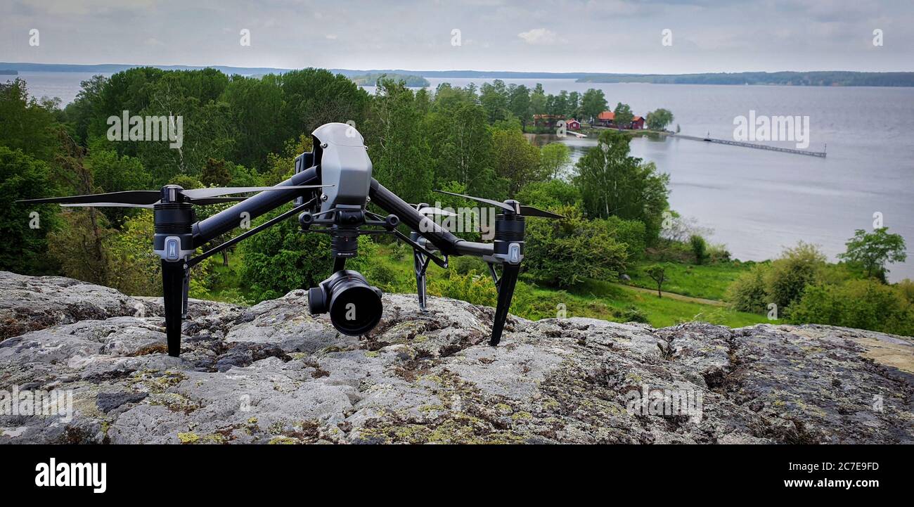 Drone sat on rocky cliff edge with green Swedish island in the background Stock Photo