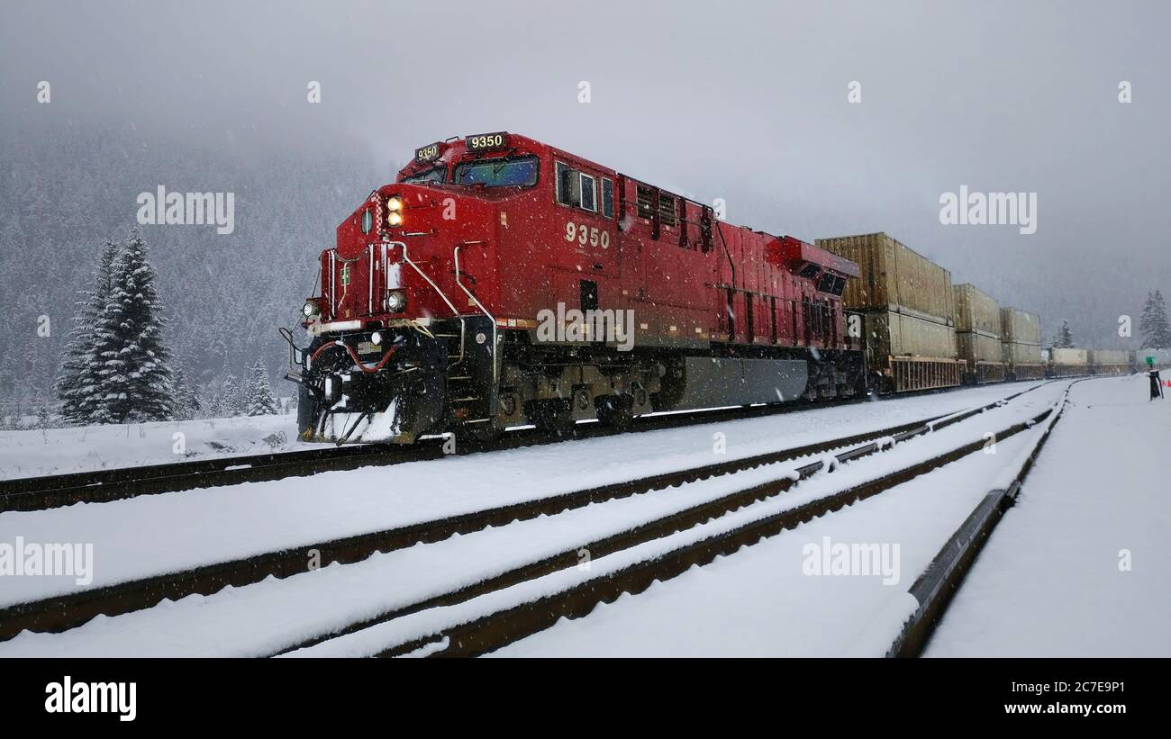 Red train engine pulling cargo in the snow Stock Photo
