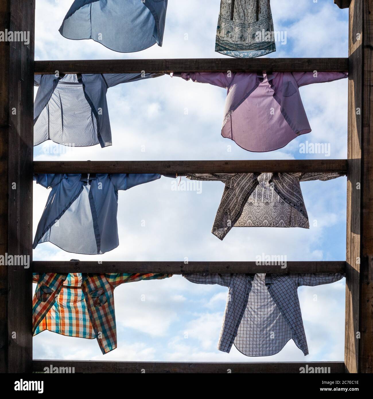 Art installation of colorful shirts clothes hanging on wooden ramp on blue sky background in Oslo, Norway Stock Photo