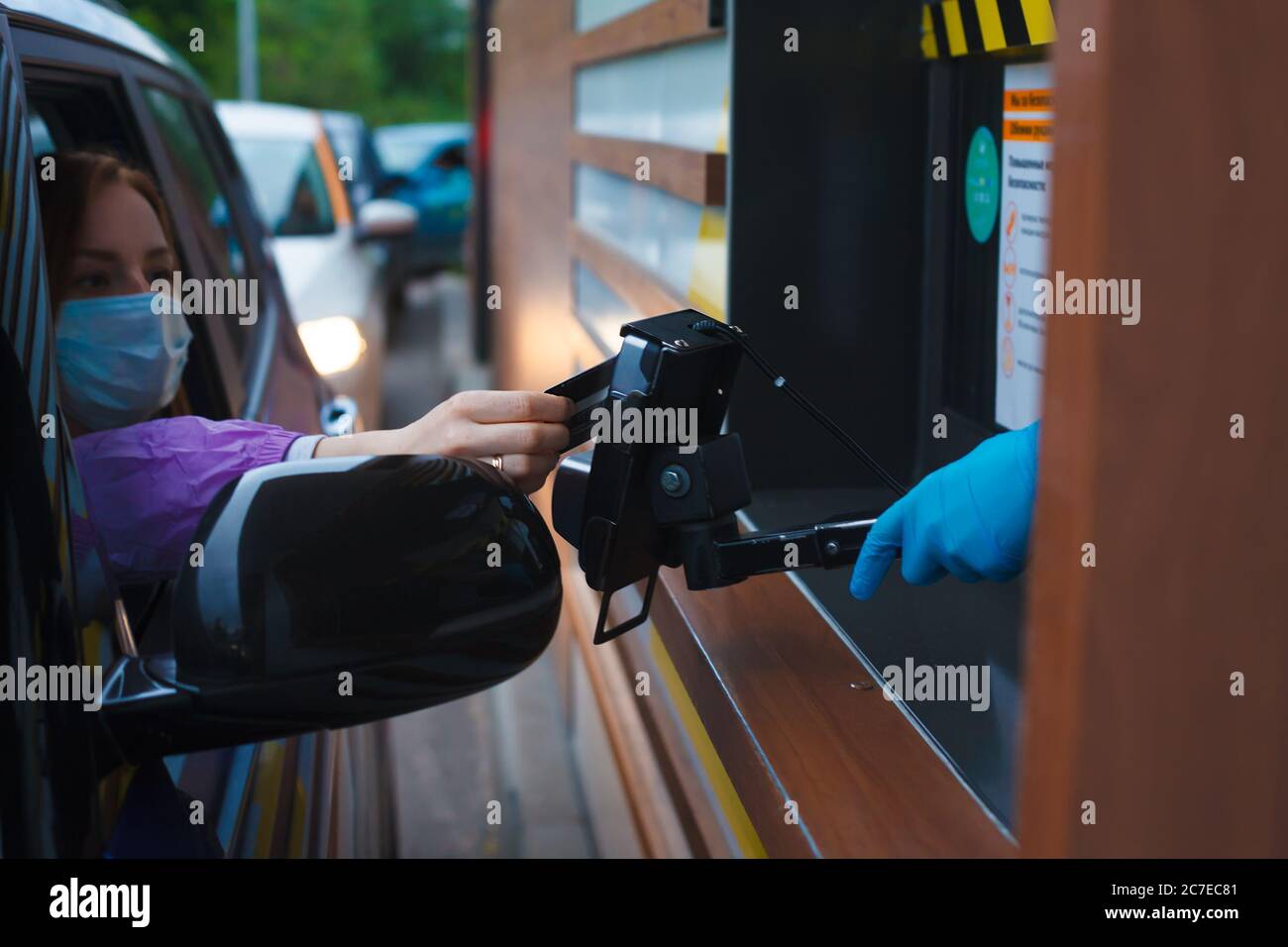 Woman in a car paying distantly by card in takeaway window Stock Photo