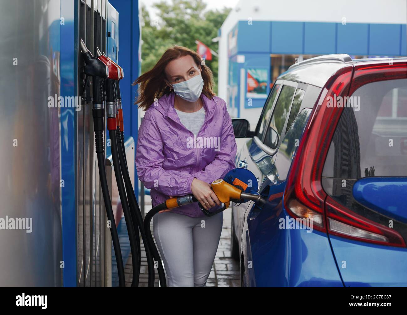 Woman in protective mask filling her car tank on a gas station Stock Photo