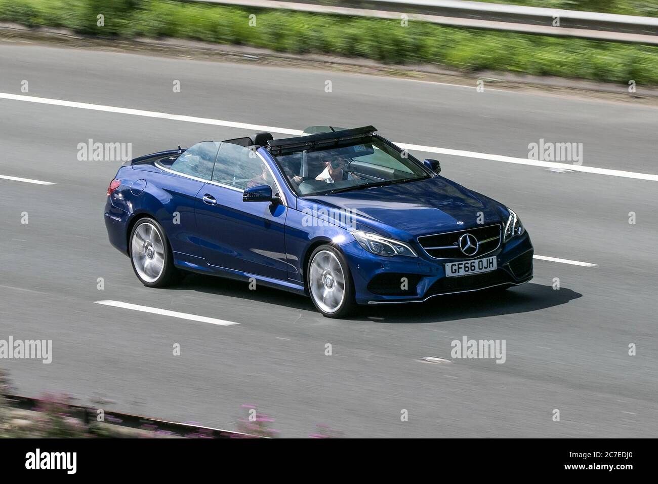 A 2016 Mercedes-Benz E 220 Amg Line Edit Prem Blue Car Diesel Cabriolet convertible soft top driving on the M6 motorway near Preston in Lancashire, UK Stock Photo