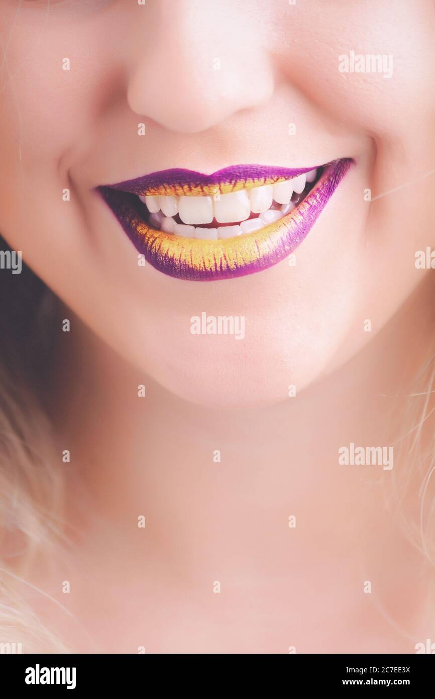 Closeup shot of a female wearing purple and yellow lipstick with a beautiful smile Stock Photo