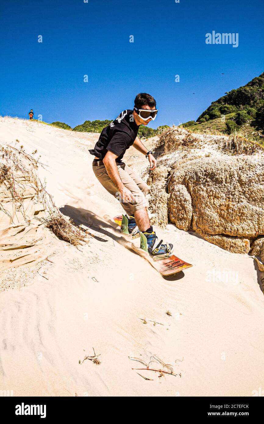 Man sandboarding on the dunes of Prainha. Palhoca, Santa Catarina, Brazil. Stock Photo
