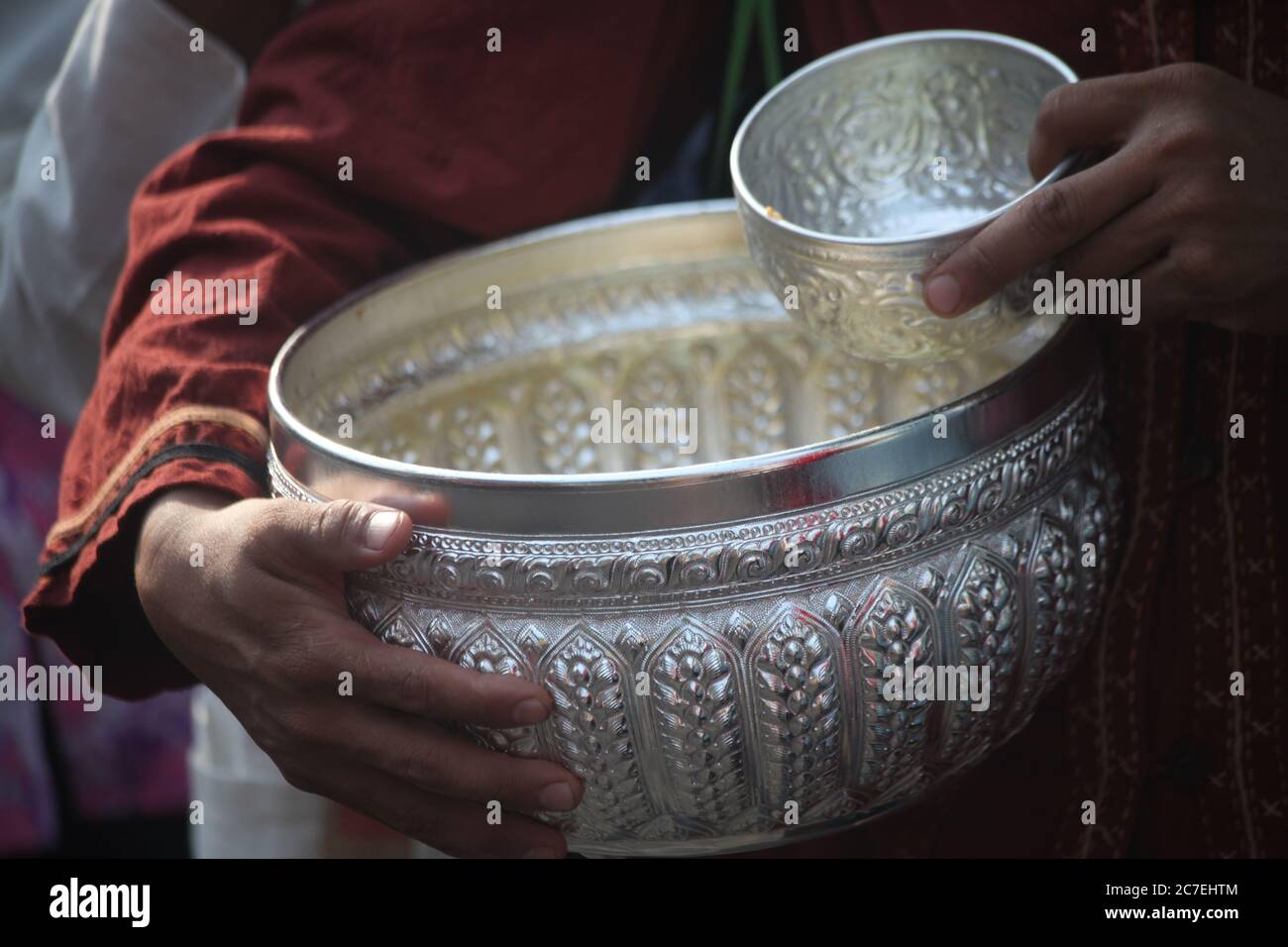 Closeup shot of two silver ritual bowls with a monk performing a ...