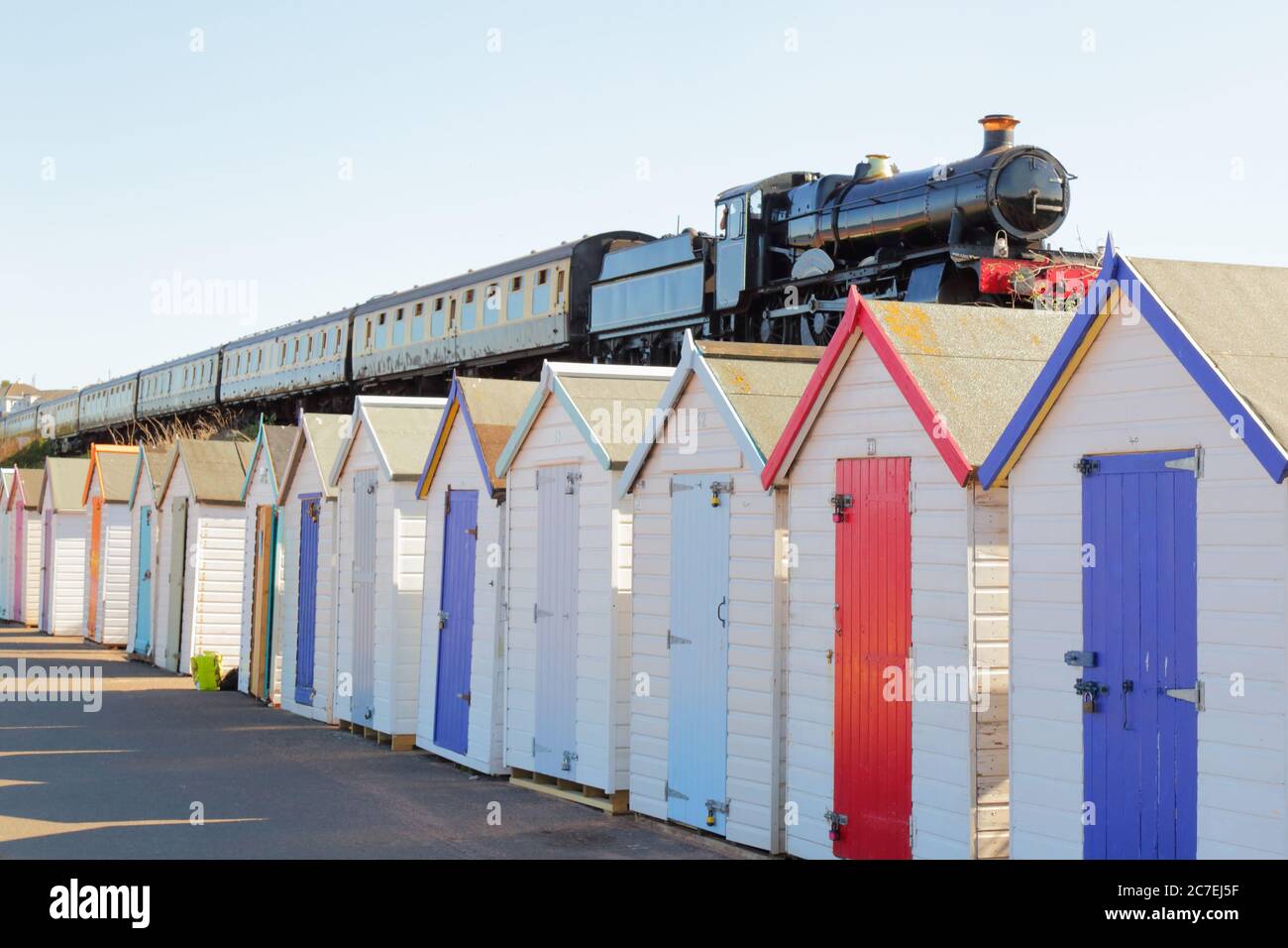Train passing colorful beach huts in South Devon, UK Stock Photo
