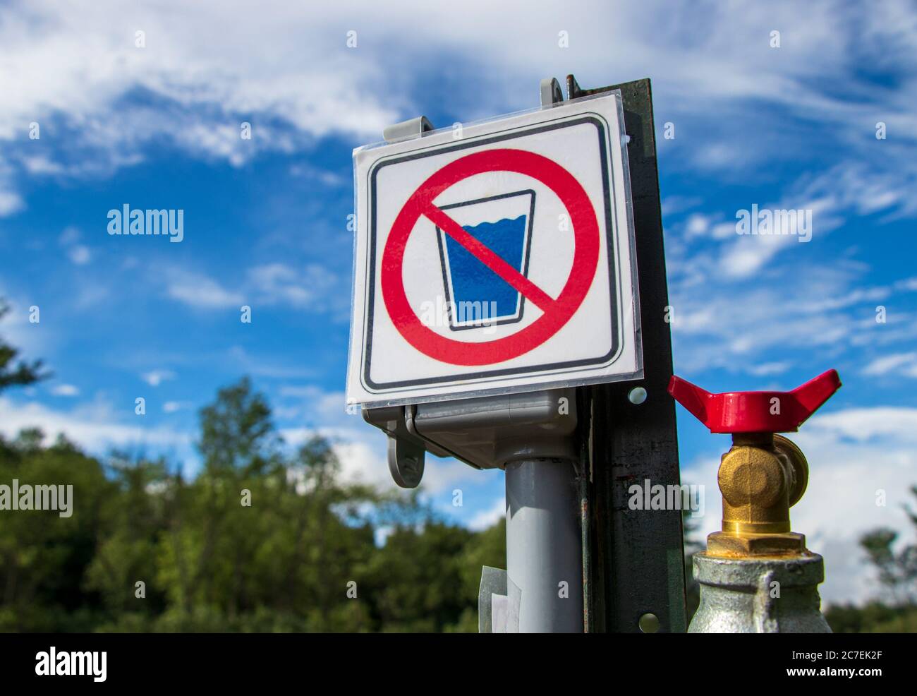 Non-potable water sign on a campground, camping site, view from below and blue sky in background, closeup Stock Photo