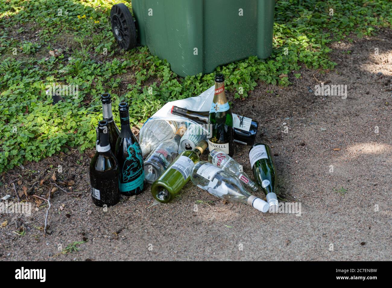 Empty bottles of beer and wine next to trash can Stock Photo