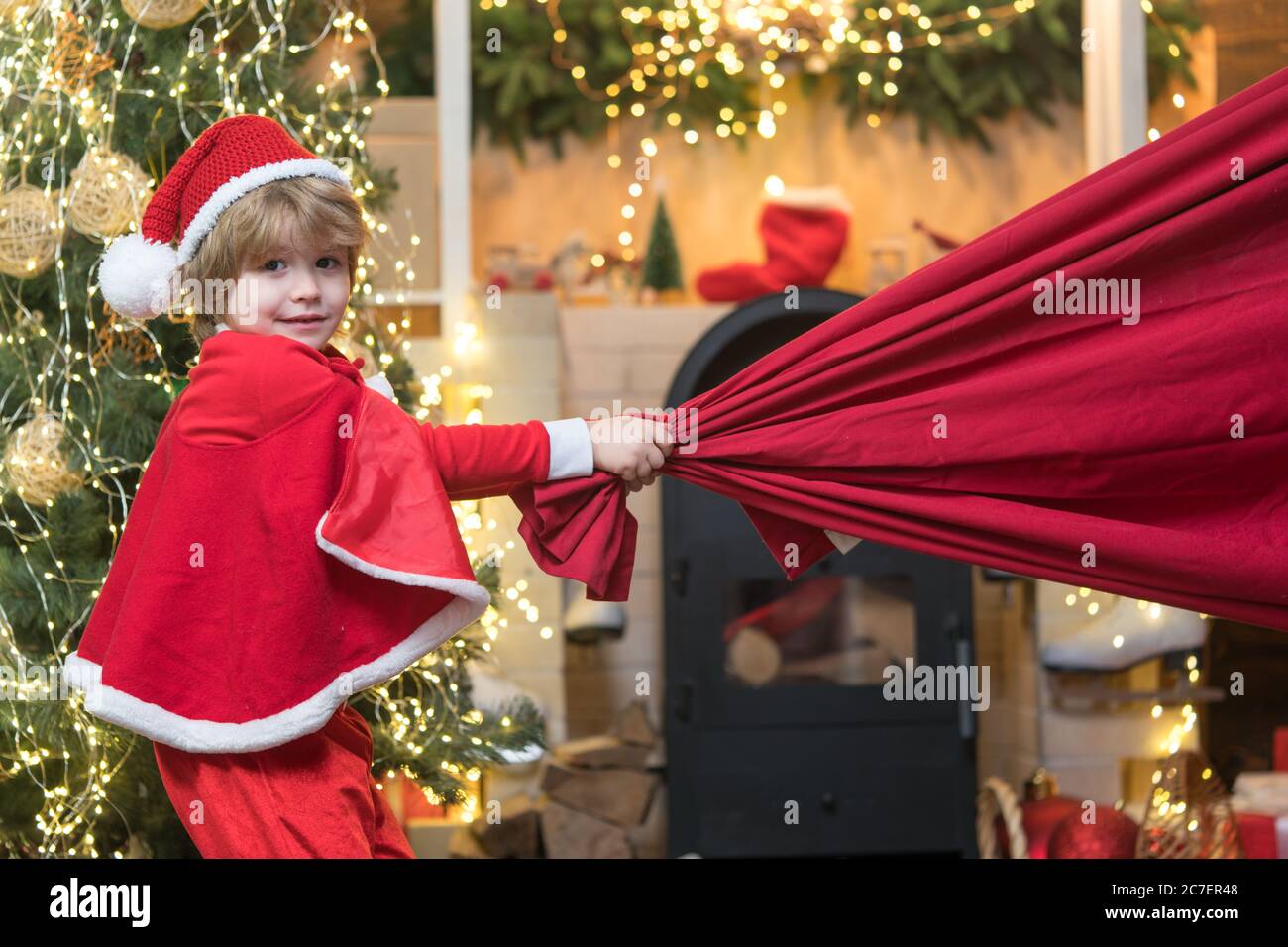 Little Santa Claus pulling huge bag of gifts on Christmas background ...