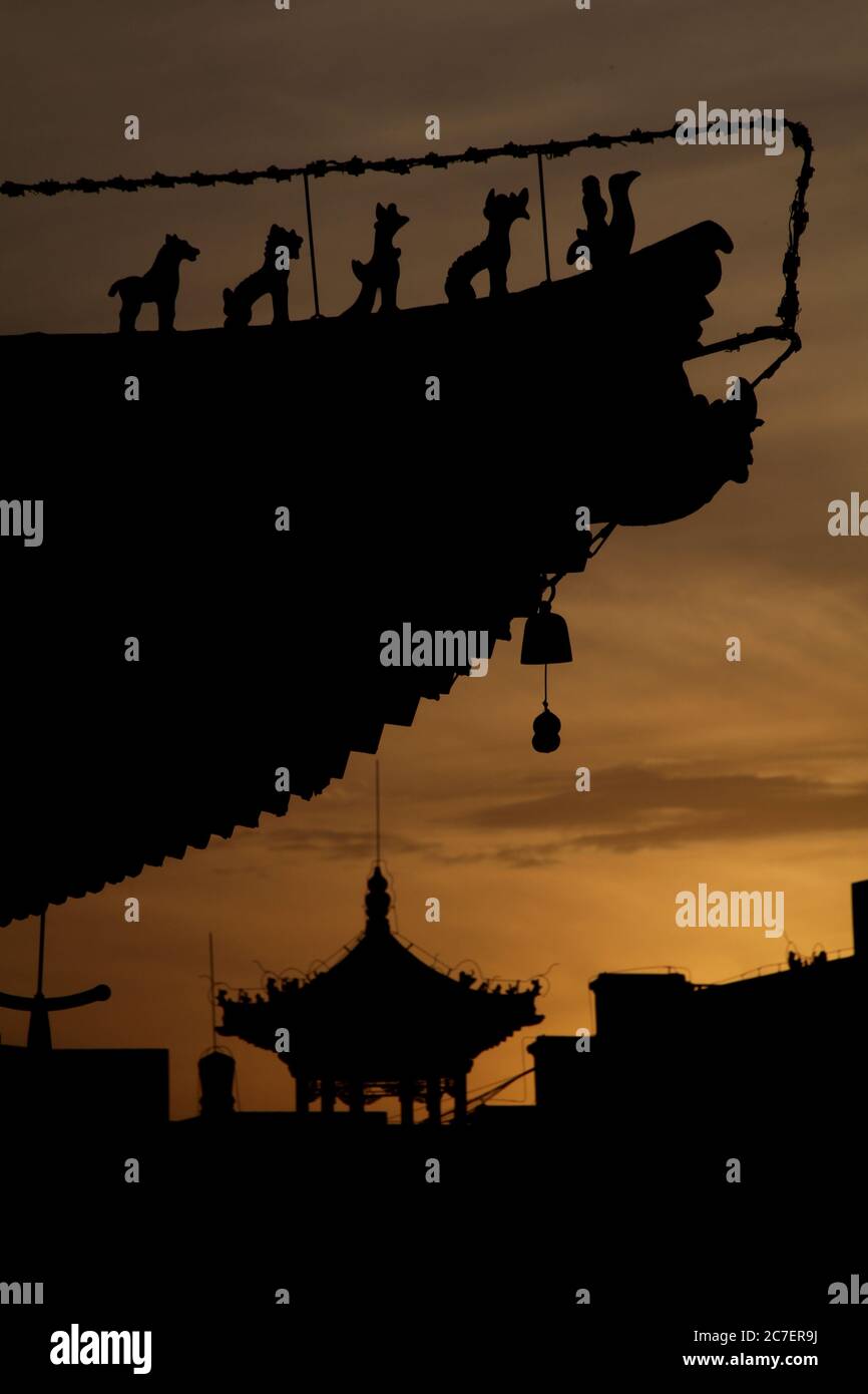 Vertical silhouette of the sunset sky in Xian with a pagoda and traditional roofing Stock Photo