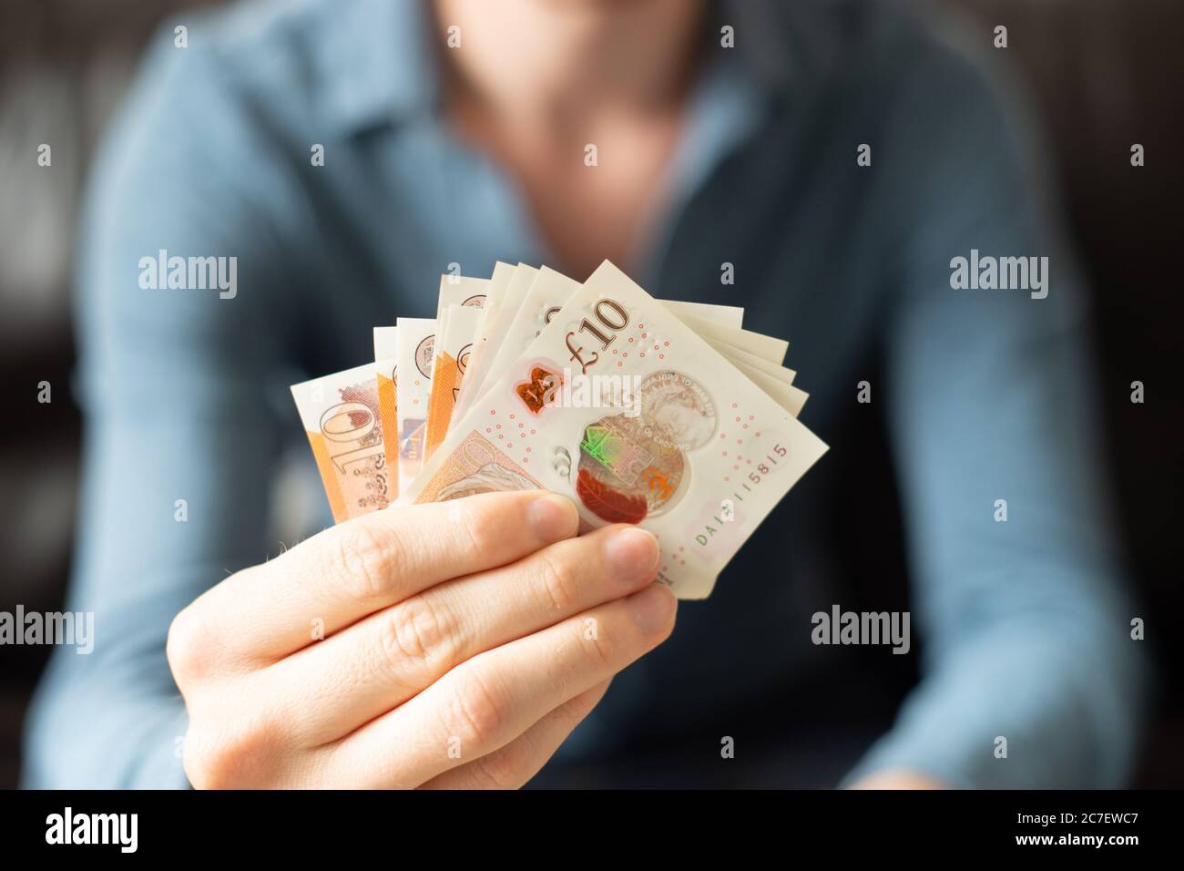 Person holding out cash, banknotes, giving money to you, for you, gift, here is some money, take it, hand, hands, pay, settle, remit, debt Stock Photo