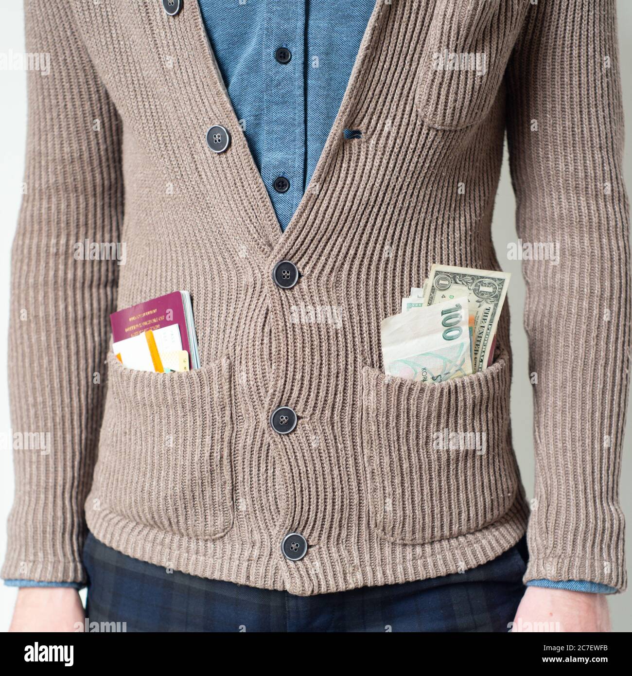 young man wearing cardigan with various currencies, passport and tickets in pocket, concept - travel, traveller, worldwide, vacation, holiday Stock Photo