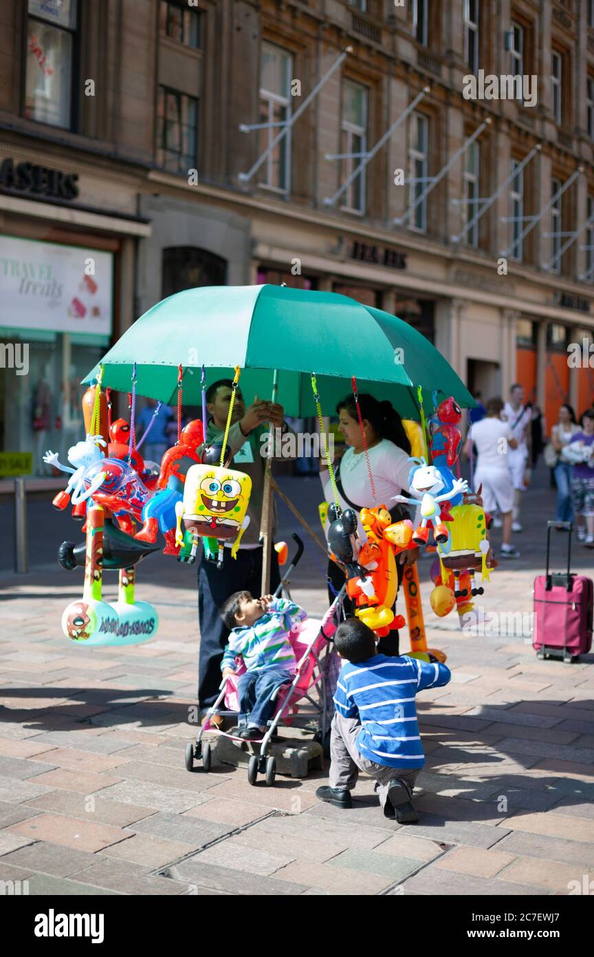Family at the bottom of Buchanan Street, Glasgow on a sunny day with parasol  and children's toys attached. Family, outing, kids, children, day trip  Stock Photo - Alamy