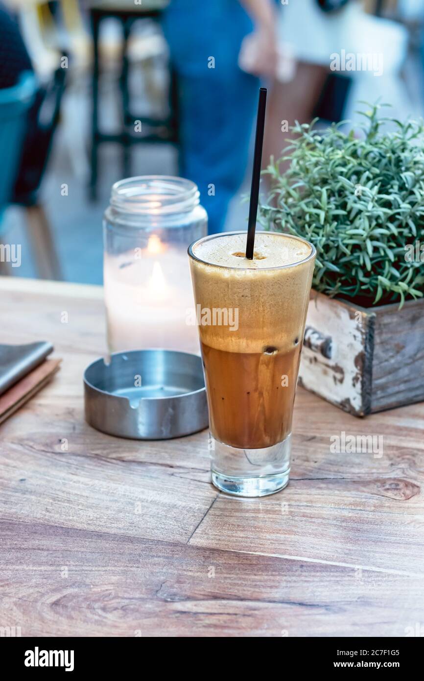 A greek cold coffee, freddo cappuccino placed on a wooden table outdoors. Stock Photo