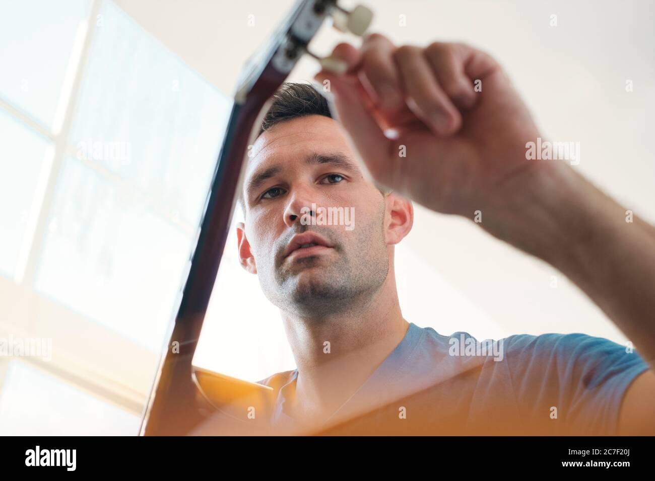 Man Tuning His Acoustic Guitar Before Playing Music Stock Photo