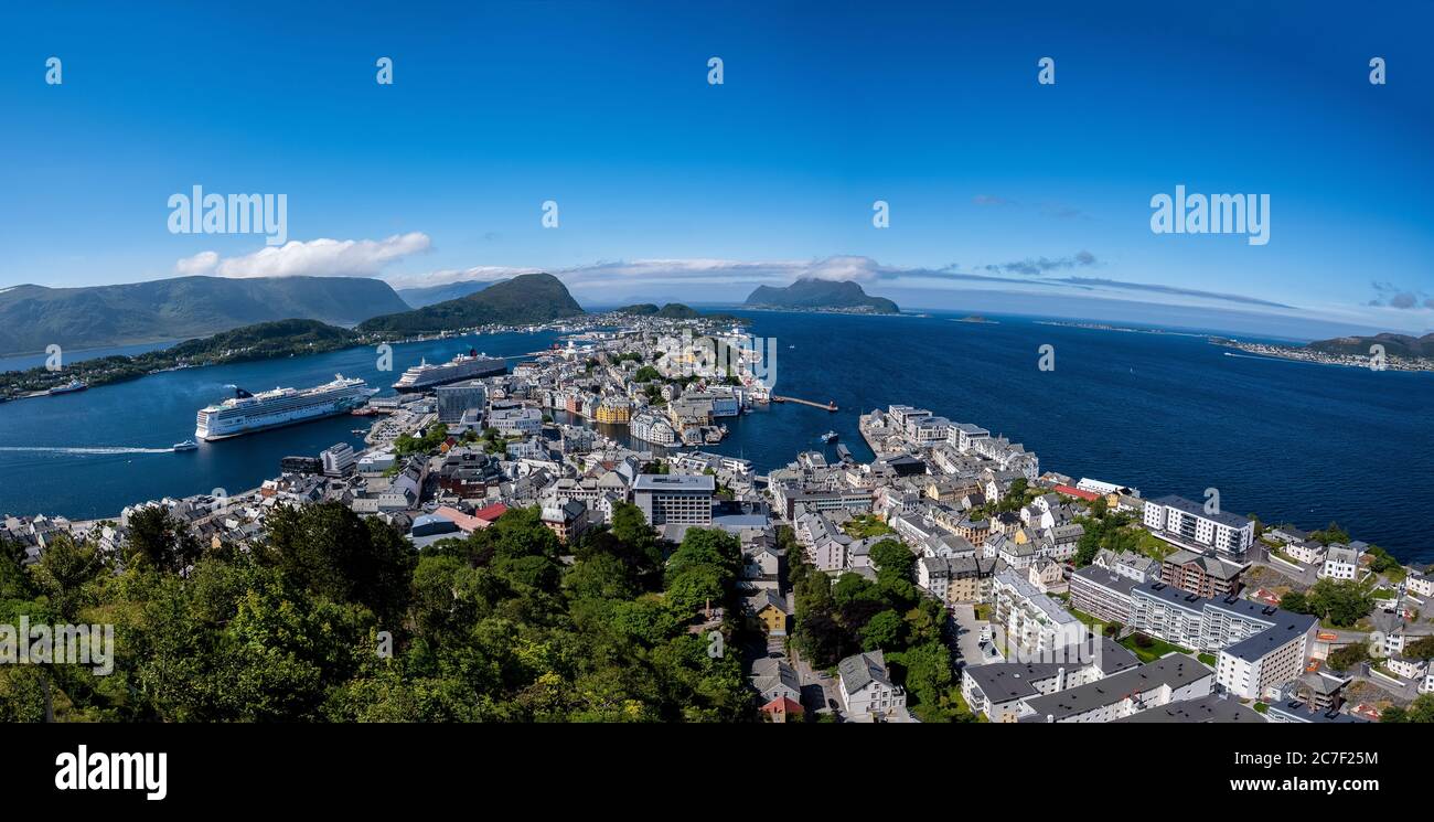 High angle shot of a lot of buildings surrounded by green trees on the shore near the sea in Norway Stock Photo