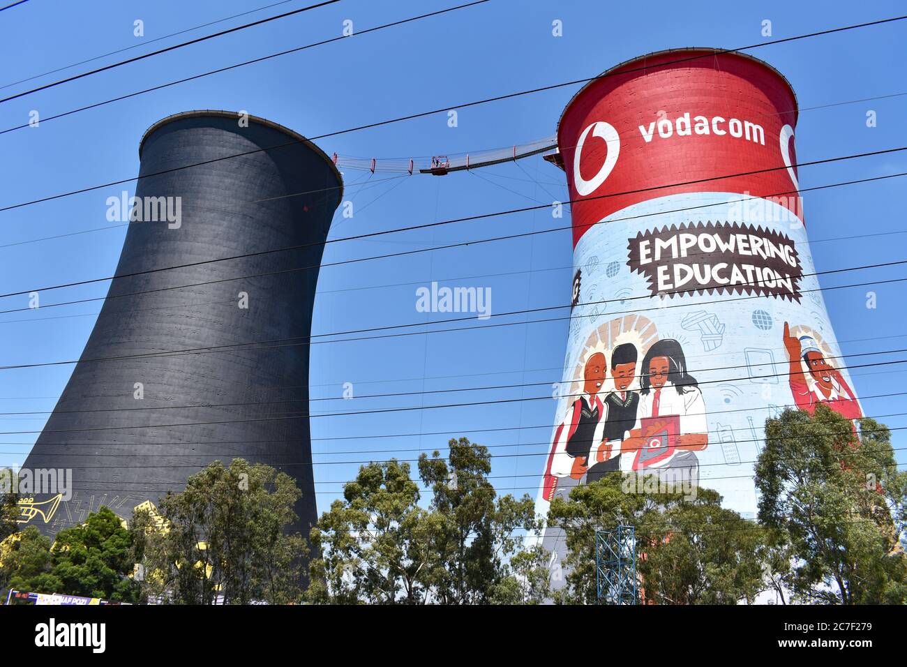 The Orlando Cooling Towers in  a suburb of Soweto. One is brightly decorated with advertising and the other is painted black. Against a clear blue sky. Stock Photo