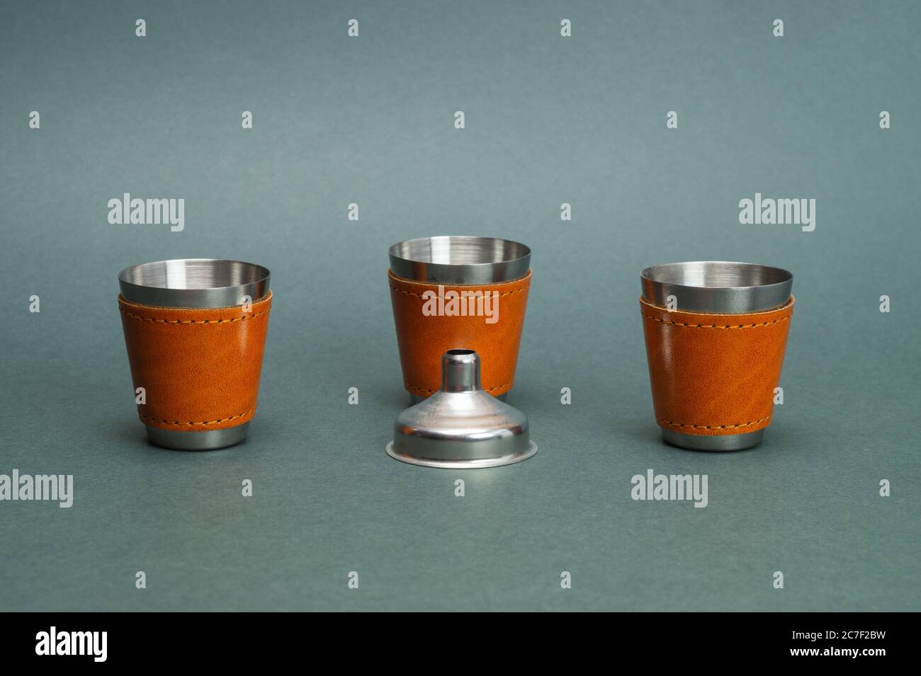 Metallic shot glasses and funnel. travel shot glass for alcohol with leather casing over the