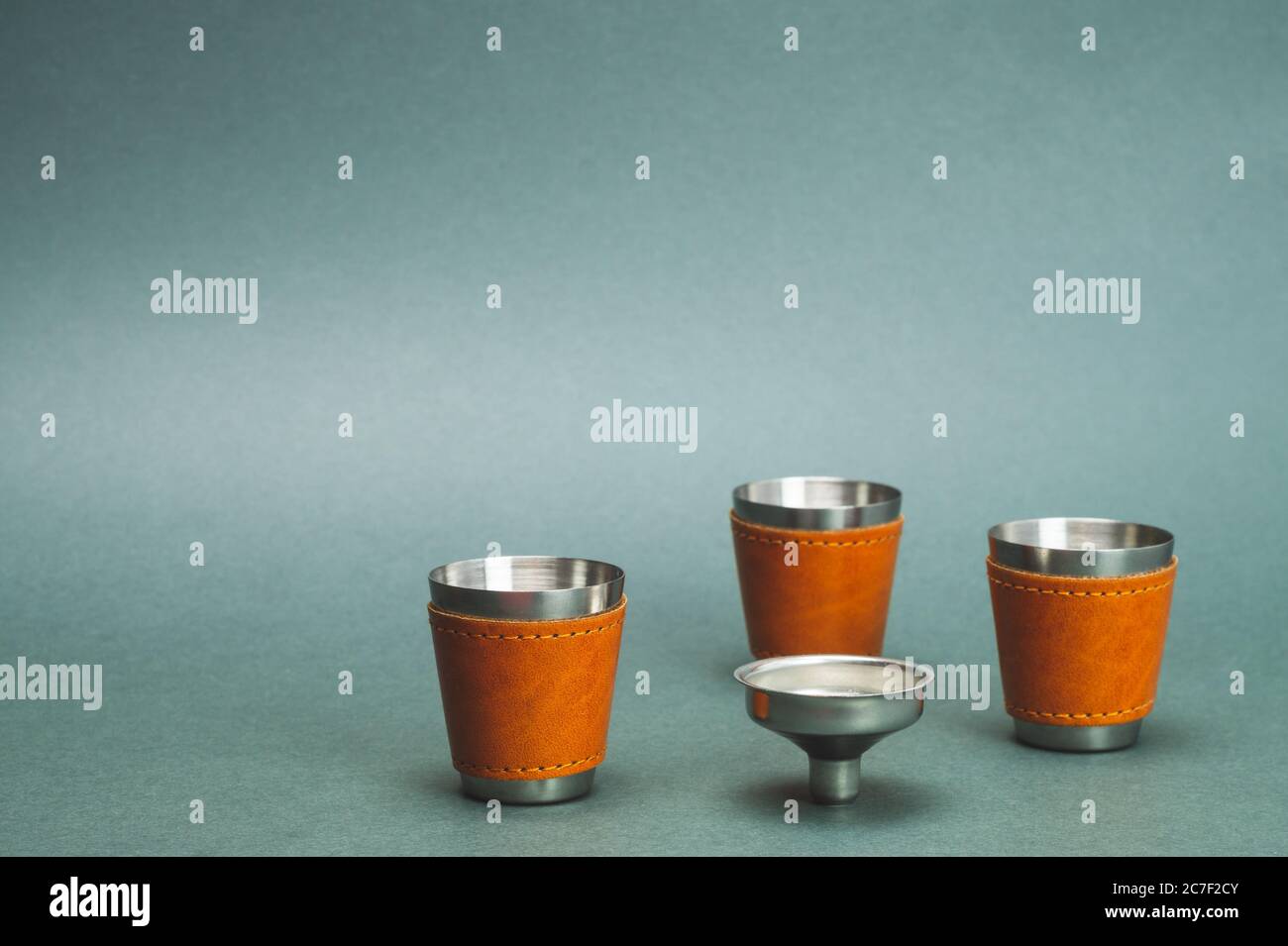 Metallic shot glasses and funnel. travel shot glass for alcohol with leather casing over the