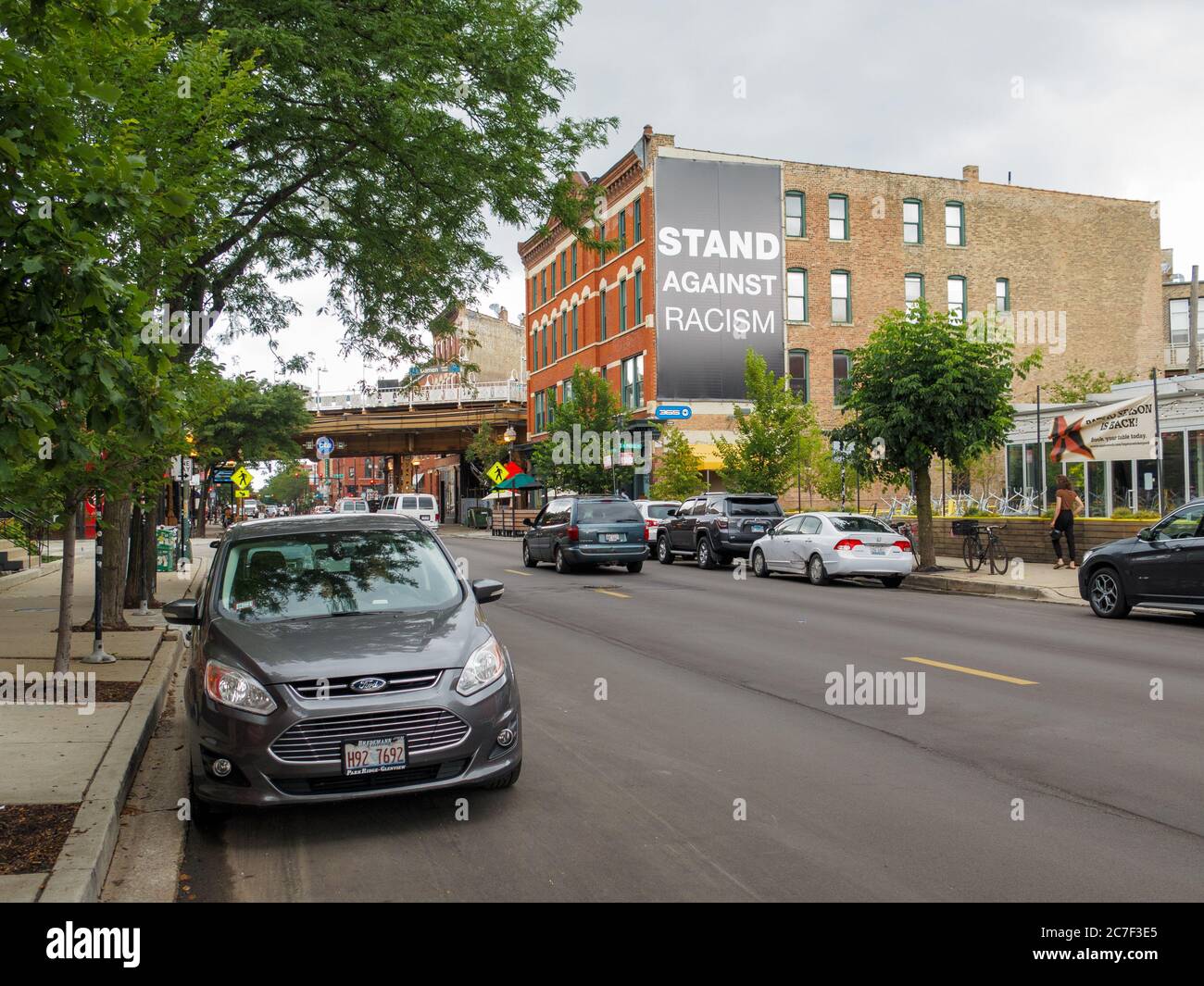 View north on Damen Avenue, Wicker Park neighborhood of Chicago. Stand against racism banner on building. Stock Photo