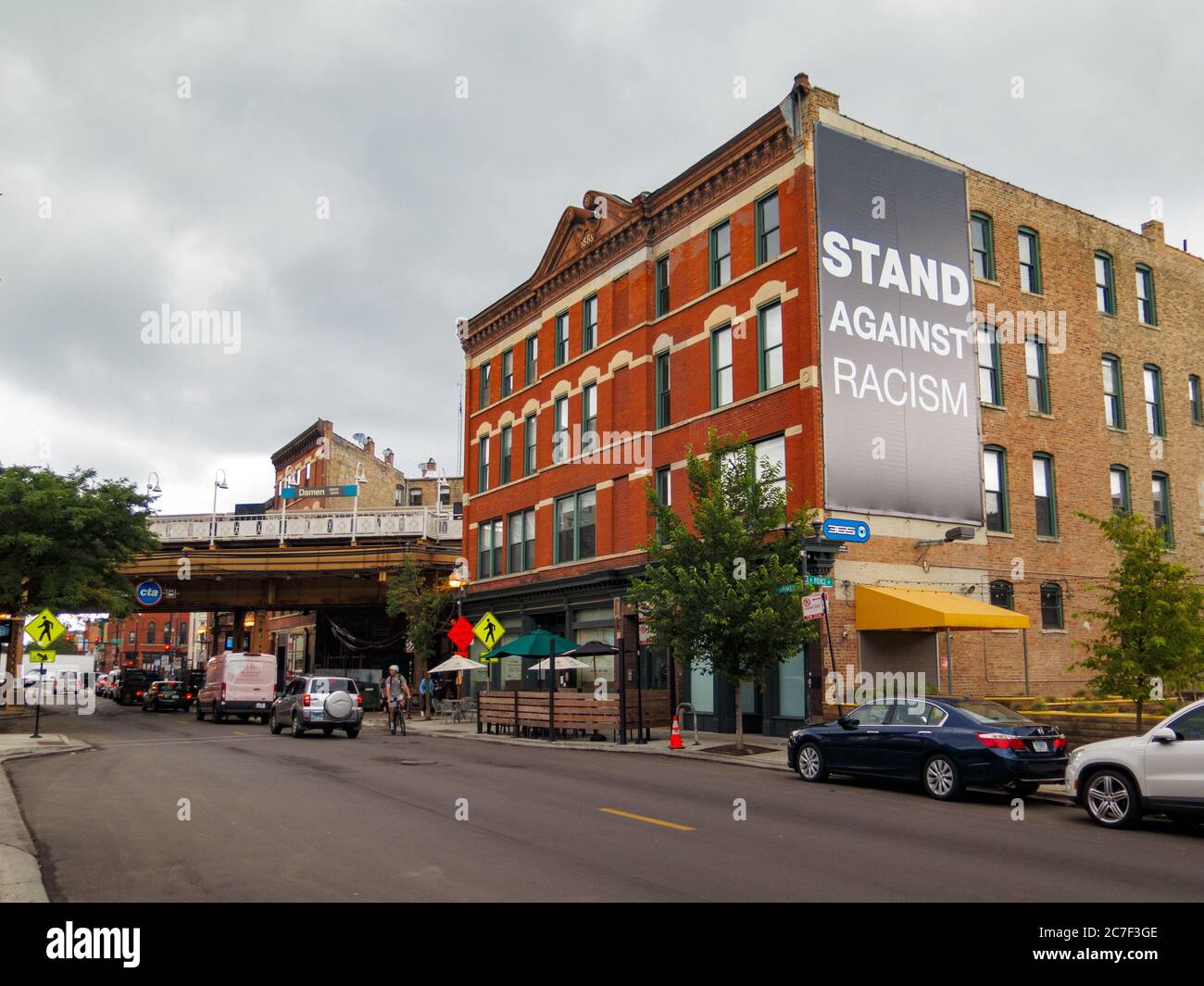 View north on Damen Avenue, Wicker Park neighborhood of Chicago. Stand against racism banner on building. Stock Photo