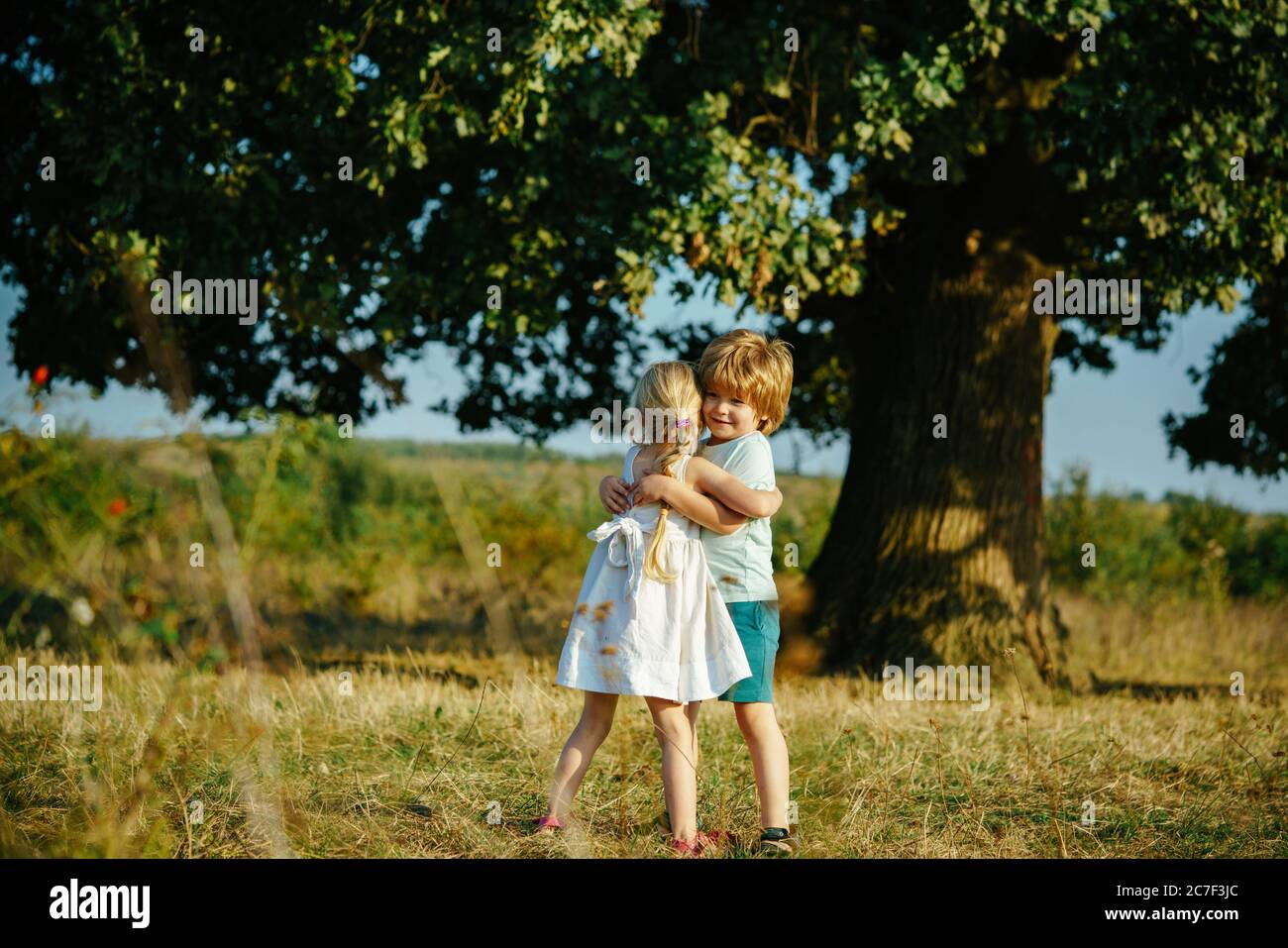 Happy little friends hugging on countryside. Child embrace each ...