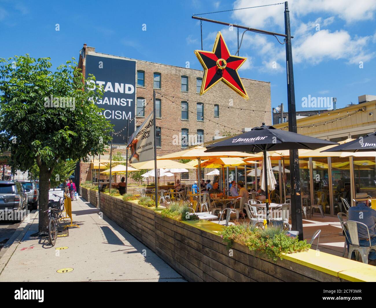 Big Star Restaurant outdoor eating area, social distancing markers on sidewalk. Stand Against Racism banner on building in background. Damen Avenue, Wicker Park neighborhood, Chicago, Illinois. Stock Photo