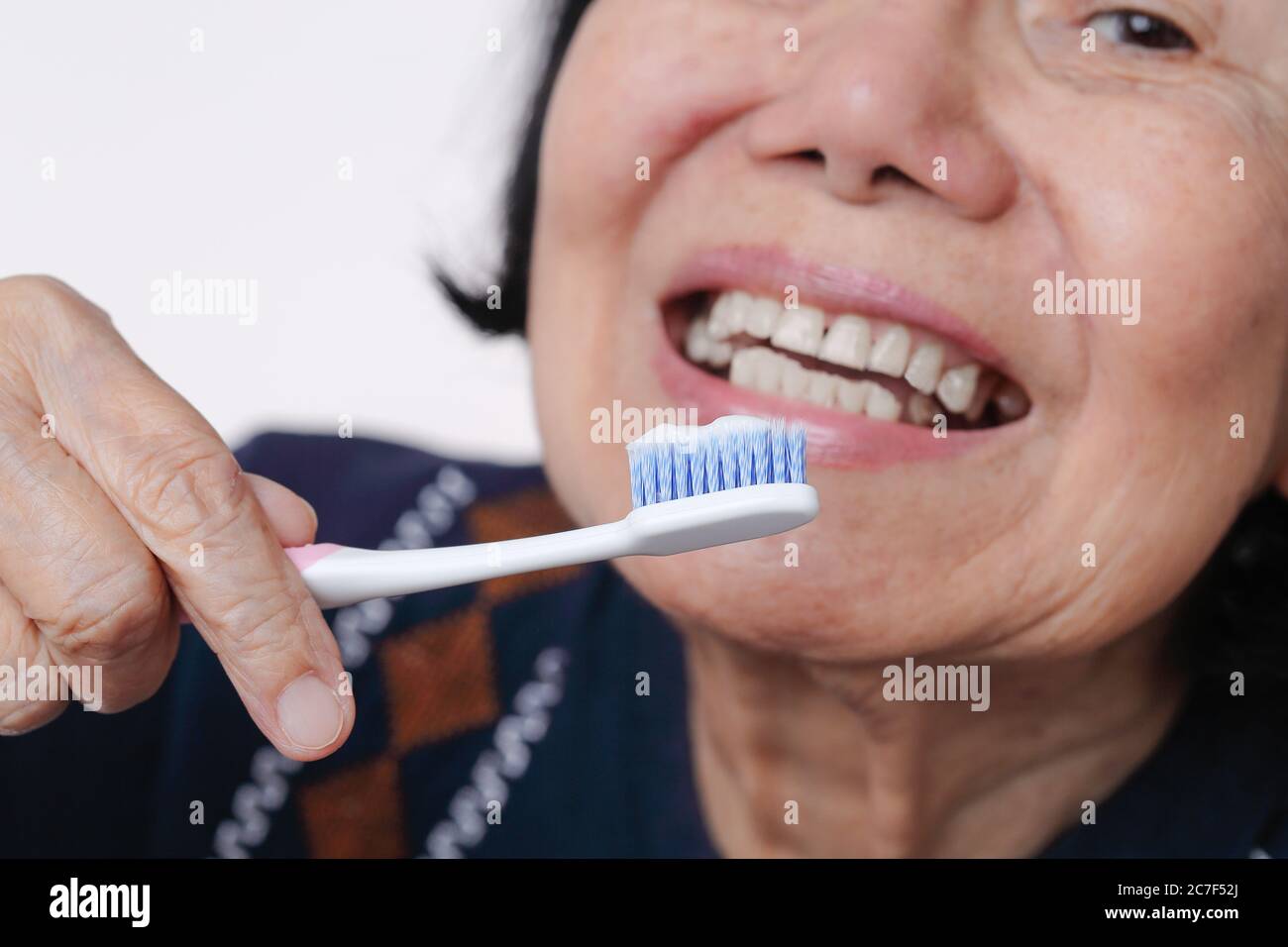 Asian elderly woman trying use toothbrush ,hand tremor . Dental health Stock Photo