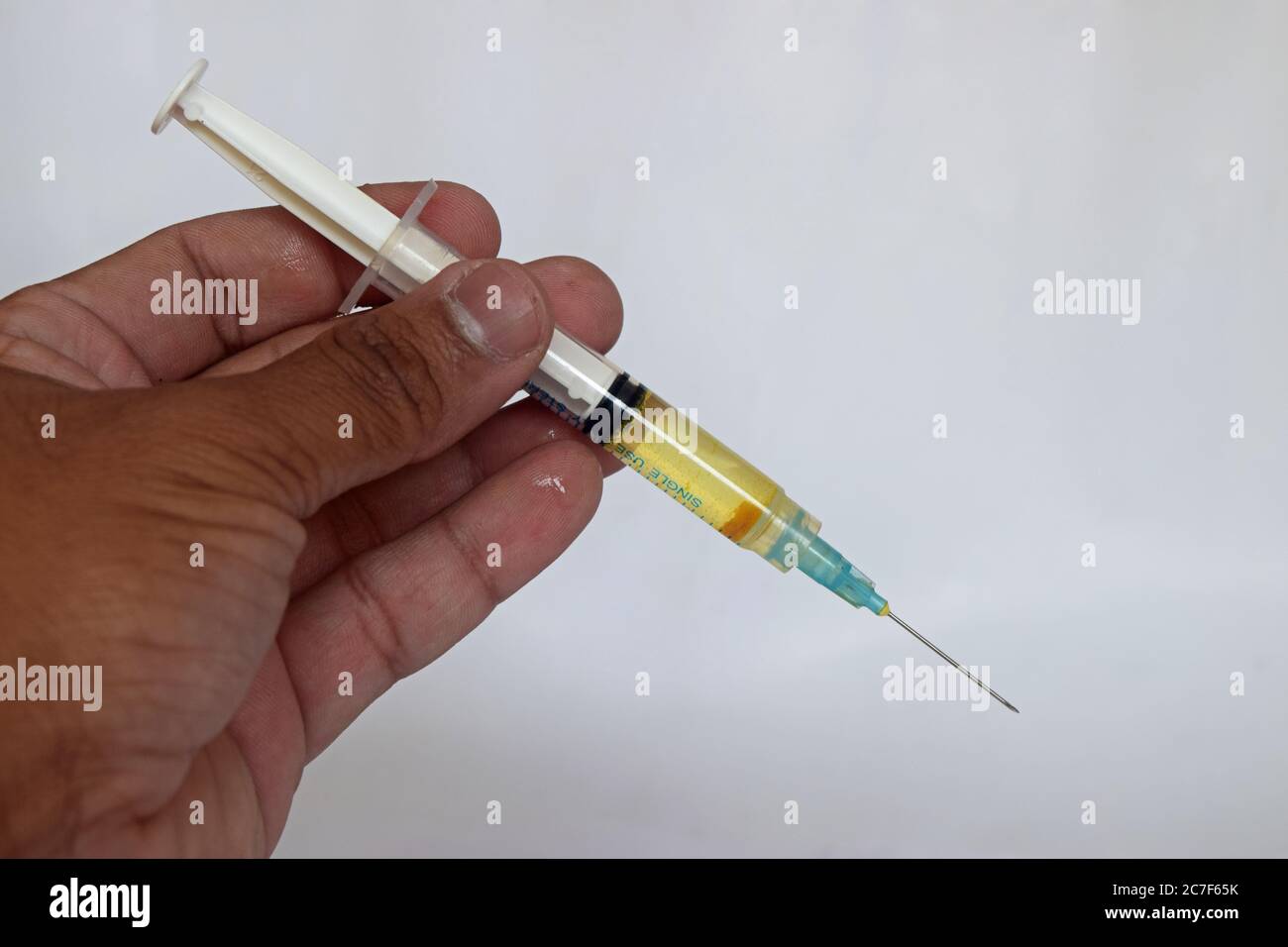 Syringe, medical injection in hand , palm or fingers. Medicine plastic vaccination equipment with needle. Nurse or doctor. Liquid drug or narcotic. Stock Photo