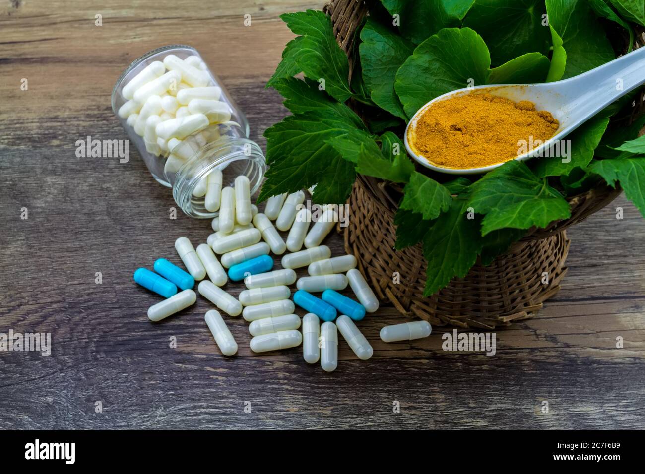 Colorful pill and yellow turmeric powder and green leaf of   White mugwort plant (Artemisia lactiflora) with Green Asiatic Pennywort (Centella asiatic Stock Photo