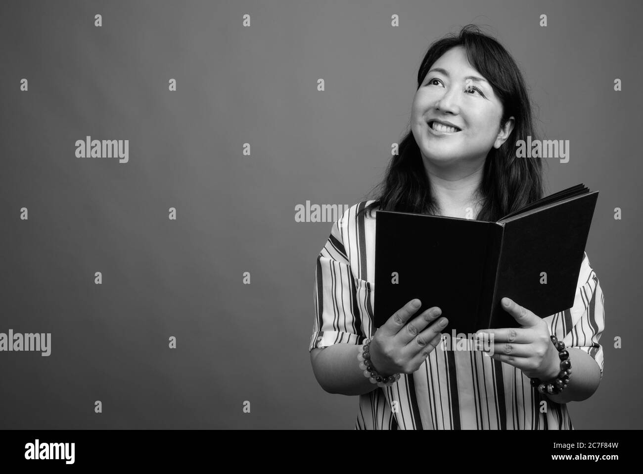 Portrait of mature beautiful Asian businesswoman with book Stock Photo