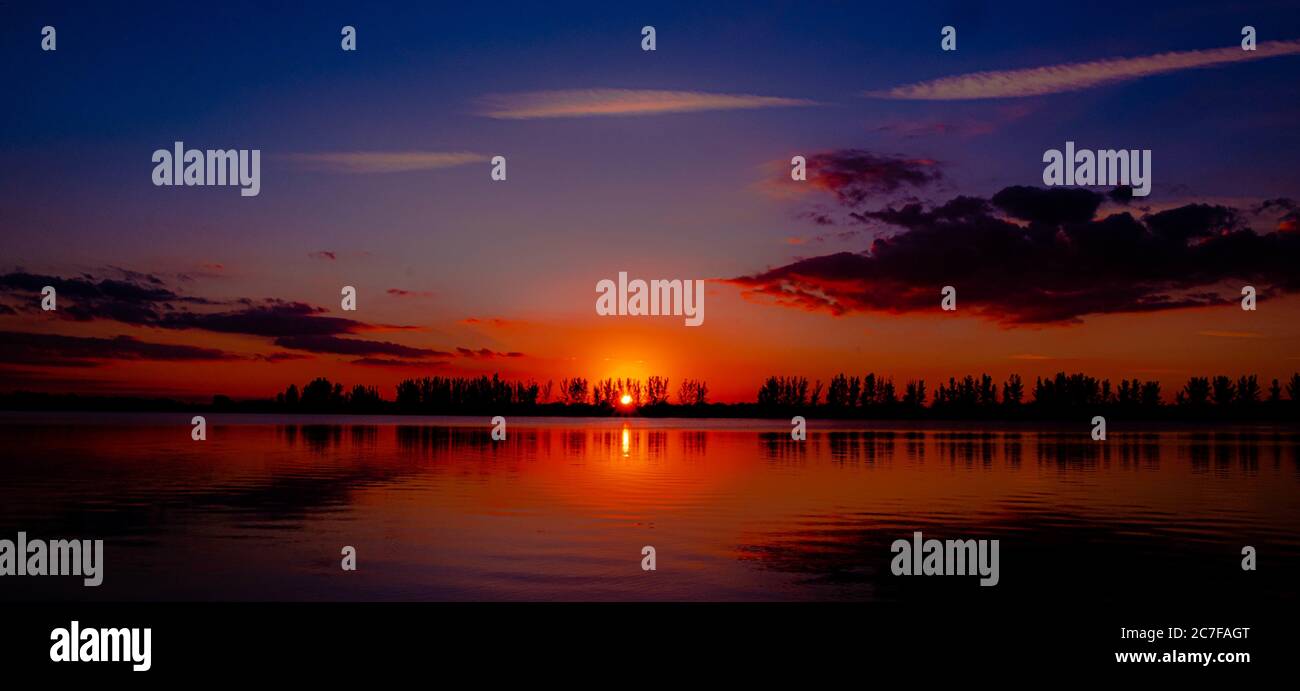Beautiful scenery of the sunset reflecting on the sea surrounded by a ...