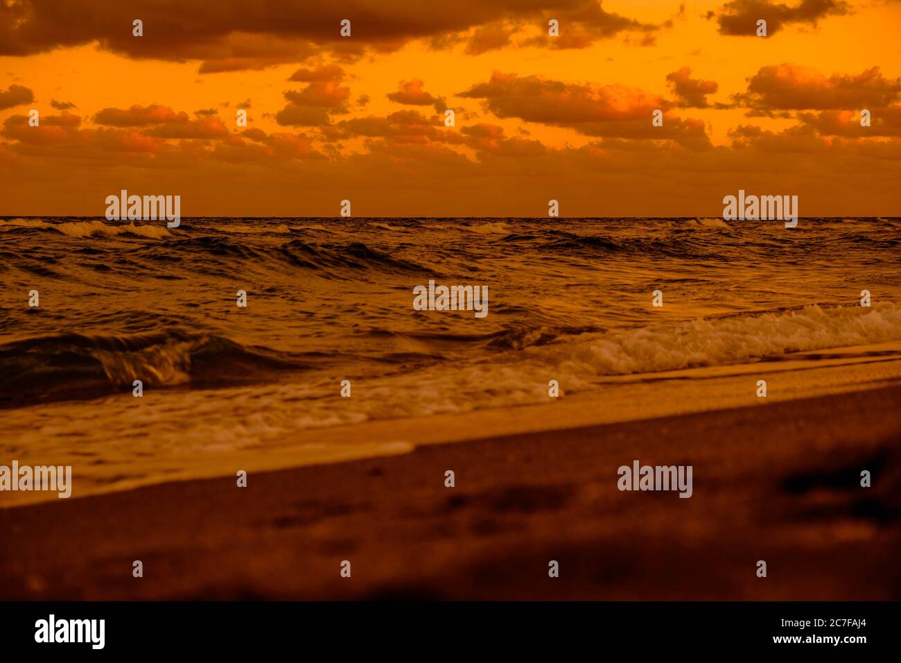 Beautiful scenery of the sunset reflecting on the sea under the golden ...
