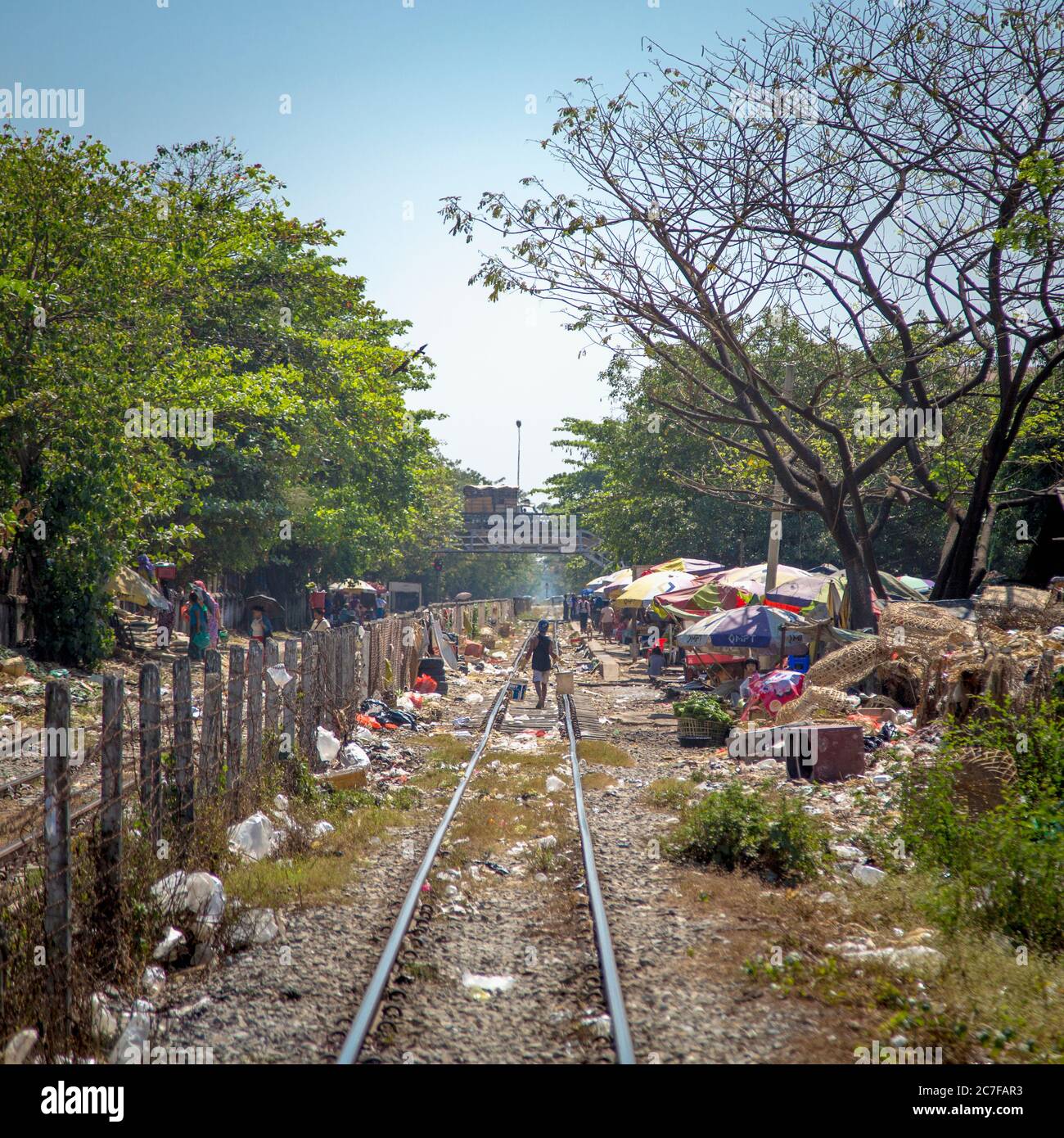 A person walking along the train tracks of the Yangon Circular railway in Myanmar Stock Photo