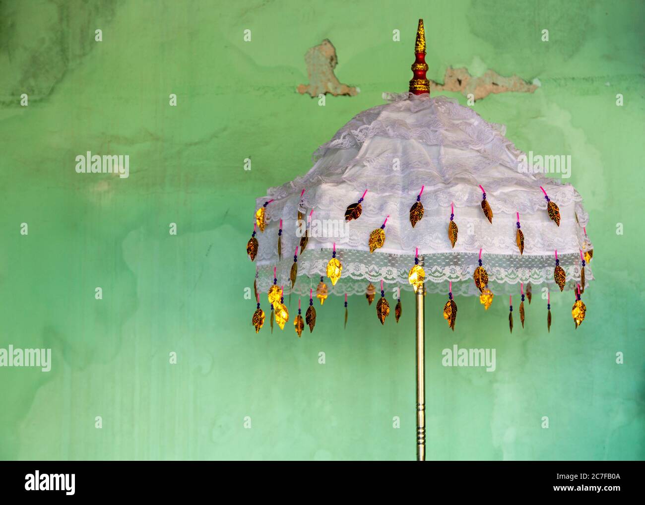 Detail of an ornamental umbrella in front of a green wall at a shrine in the Shwedagon Pagoda in Yangon, Myanmar Stock Photo