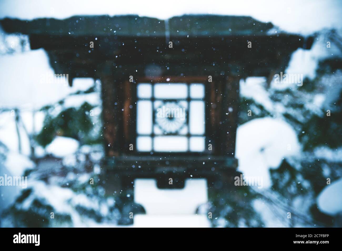 Mesmerizing scenery of snow falling over a temple lantern in Japan Stock Photo