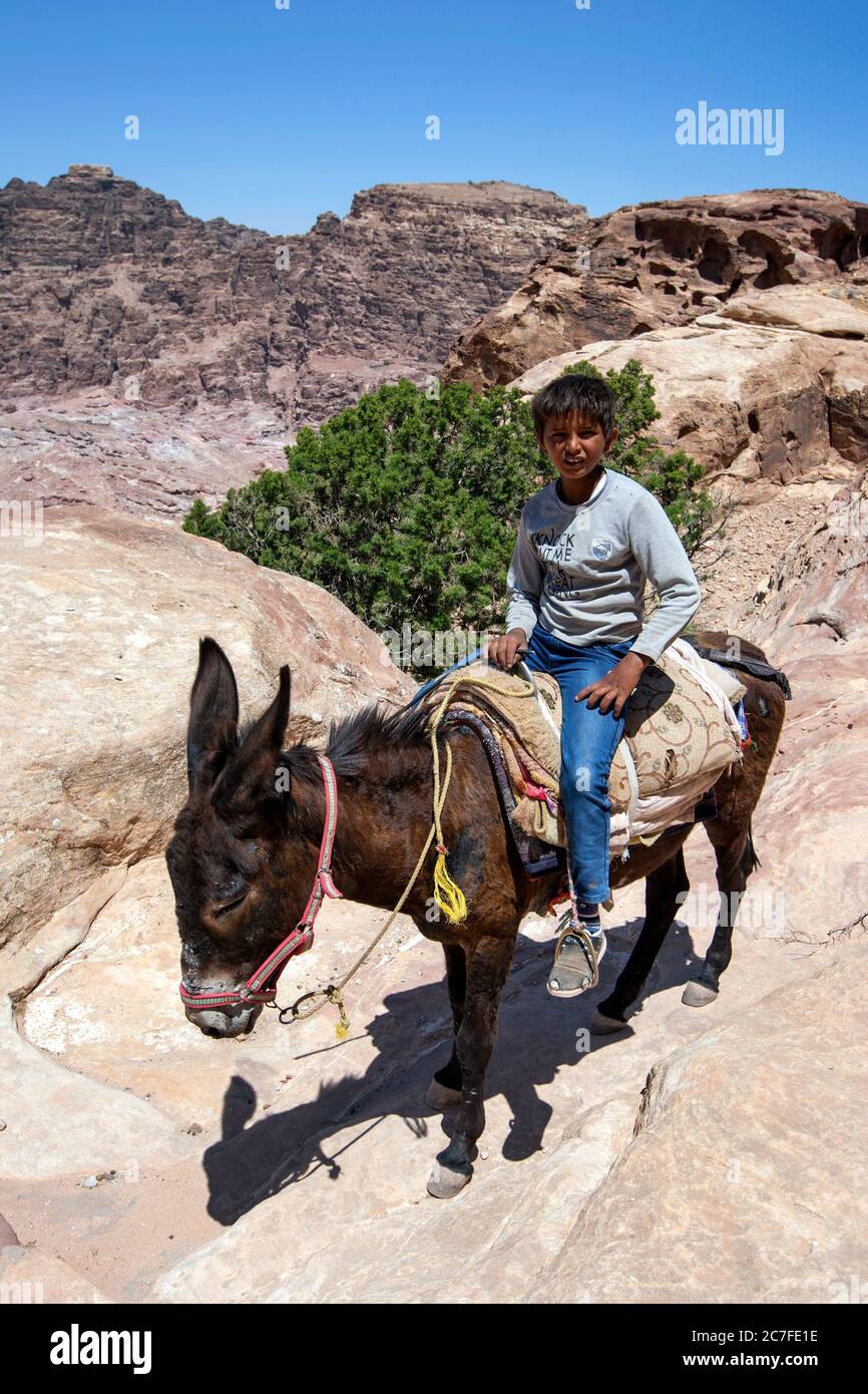 A Bedouin boy rides his donkey near the High Place of Sacrifice at Petra in Jordan. Petra was possibly established as early as 312 BC. Stock Photo