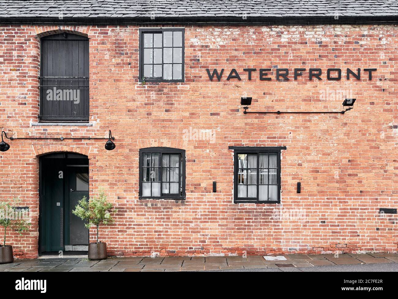 Former warehouse converted to hospitality building at the Market Harborough Arm of the Grand Union Canal on a dreary, rainy, summer day. Stock Photo