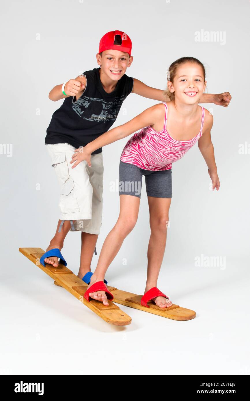 Indoor playground  2 children aged 8-12 attempt to walk together on wooden walking skies On white Background Stock Photo
