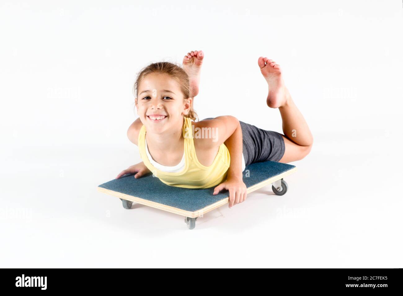 Indoor playground girl plays on wheeled board On white Background Stock Photo