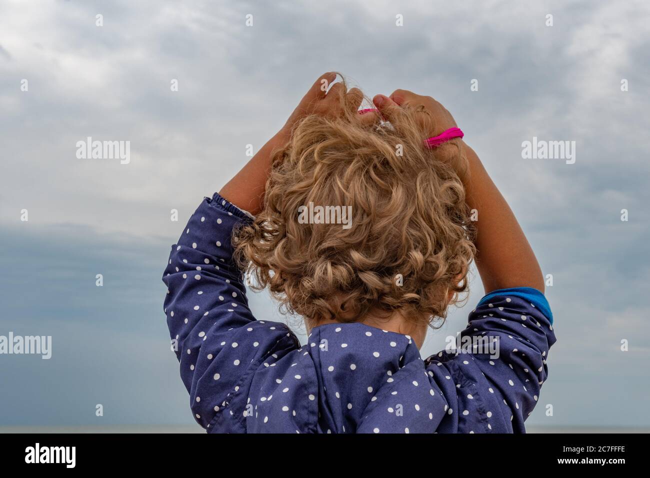 Beautiful curly hairs of little kid rising hands up in front of