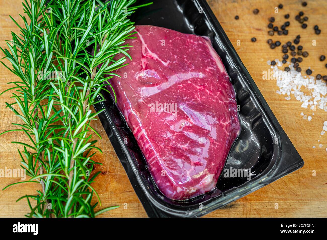 Beef steak in vacuum skin packaging and spices on wooden chopping board Stock Photo