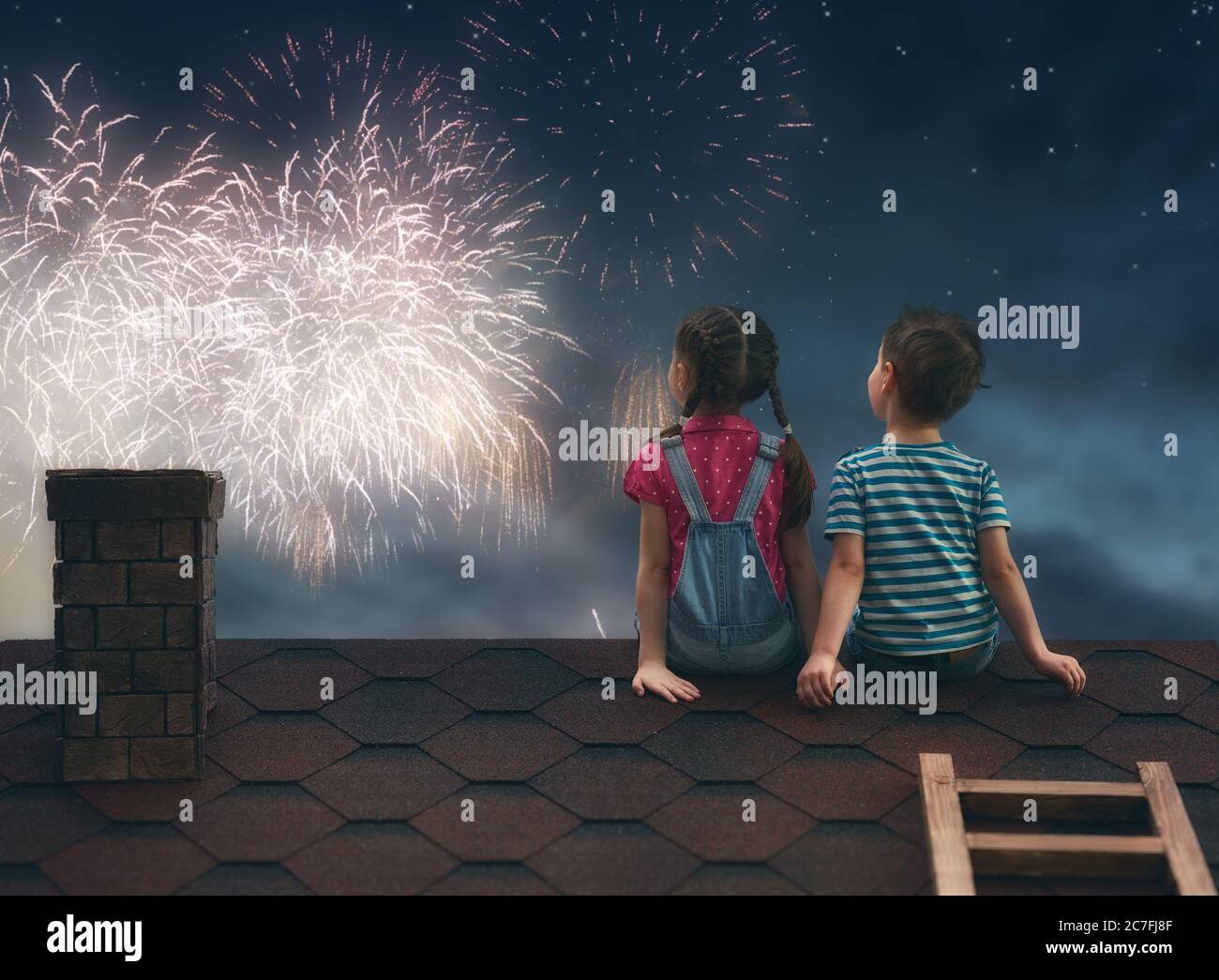 Two cute children sit on the roof and look at the fireworks Stock Photo ...