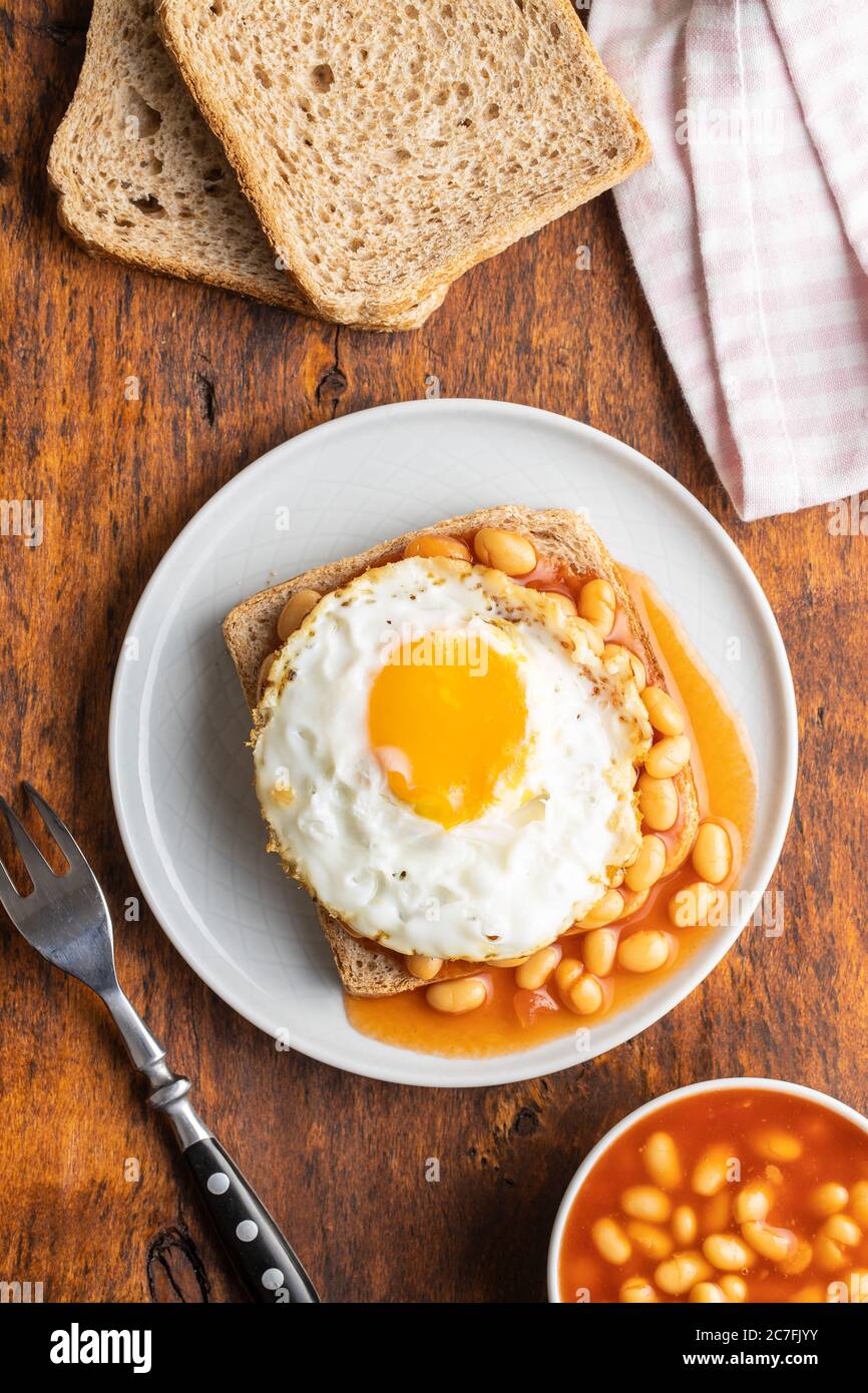Toast with fried egg and baked beans on plate. Top view. Stock Photo
